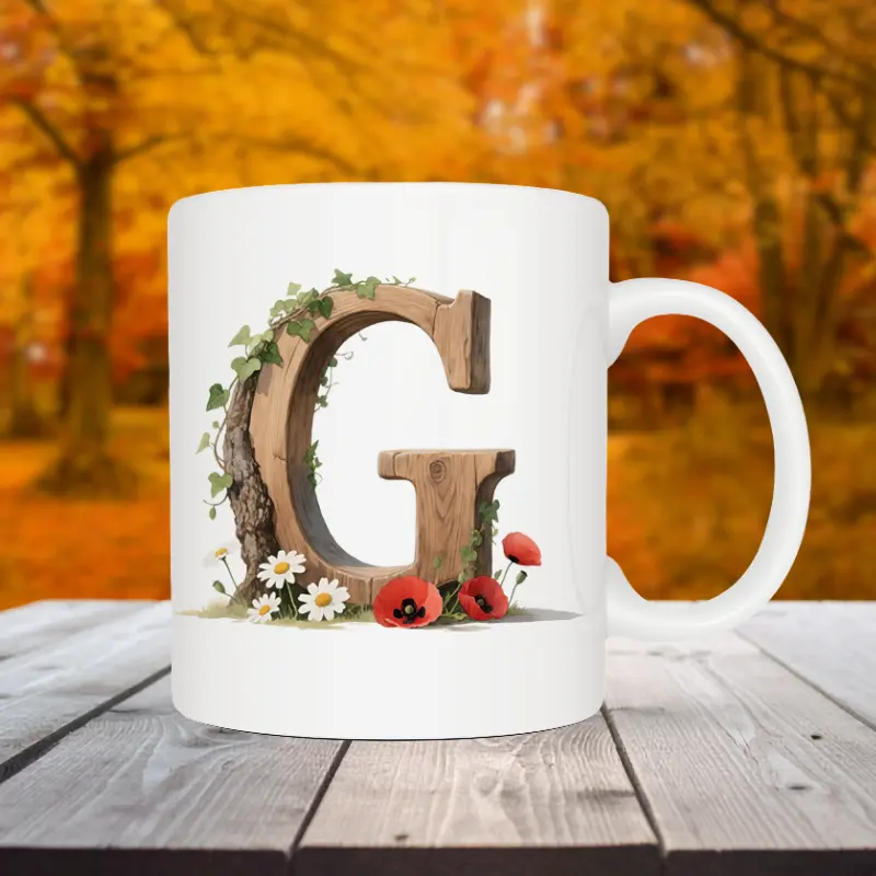 Mok letter G met standaard oor in bosthema Sfeerafbeelding van een witte mok met een opdruk van een houten letter G met klaprozen, bloemen en klimop.