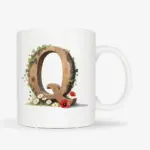 Witte mok met een opdruk van een houten letter Q met klaprozen, bloemen en klimop.